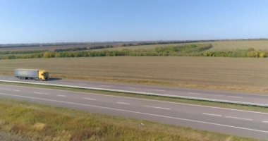 Kamyon güneşli havada tarlalar boyunca sürer. Güzel bir yolda kamyon sürüyor. Kamyon tarlaların üst manzarası boyunca gidiyor..