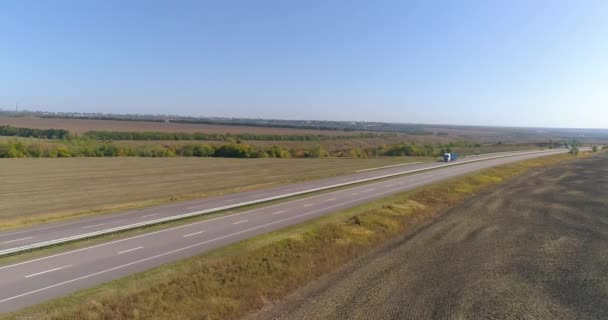 Egy teherautó halad végig az autópályán. Kilátás egy drónról. A kocsi kanyargós úton halad a mezők között. — Stock videók