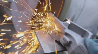 Parçalama çarkının bir parçasını öğütmekten kıvılcımlar çıkıyor. Değirmen çarkında metal bir parça işleniyor. Parlak kıvılcımlar metal bir parçayı makinelemekten.