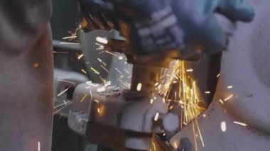 Parlak kıvılcımlar metal bir parçayı makinelemekten geliyor. Parçalama çarkının bir parçasını öğütmekten kıvılcımlar çıkıyor. Değirmen çarkında metal bir parça işleniyor..