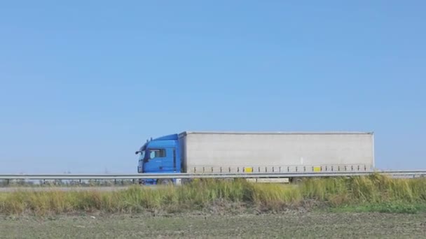 Ciężarówka jedzie autostradą. Ciężarówka jeździ po autostradzie wokół pól i drzew — Wideo stockowe