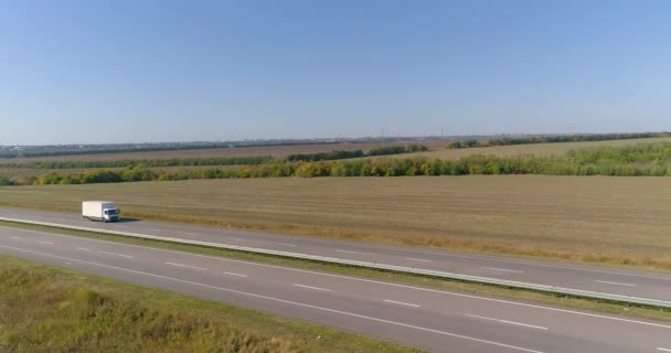 El camión conduce a lo largo de la carretera en medio de campos agrícolas vista superior. El camión conduce en la carretera, campos en el fondo — Vídeo de stock