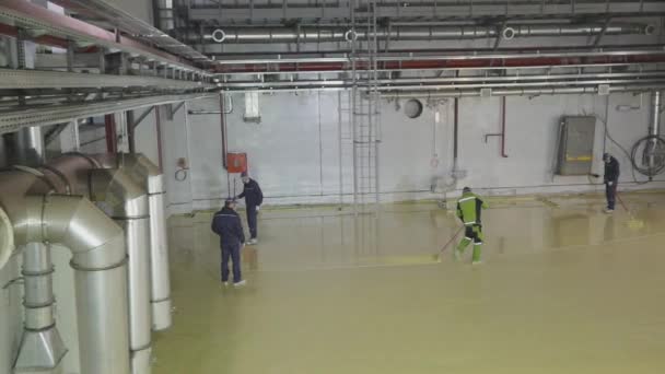 Builders make a self-leveling floor in a factory. Construction of a new workshop at the plant. Workers make a self-leveling floor in the workshop of the plant. — Vídeo de stock