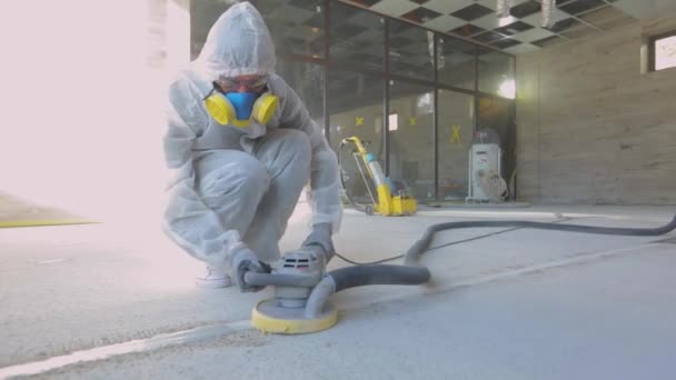 Construction professionals. Working process at a construction site. Workers in protective suits are grinding the concrete floor. Workers make concrete floor — Stock Video