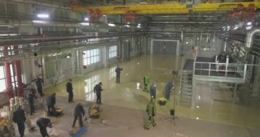 İnşaatçılar fabrika atölyesinde kendi kendine döşeme döşemesi yapıyorlar. Geniş bir alanda kendi seviyesini yükseltiyor. Atölyede kendi seviyesini yükselten zemin
