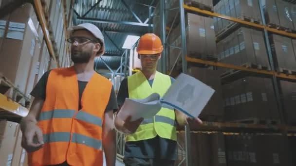 Er lopen twee mensen door het pakhuis. Twee mannen lopen door een modern pakhuis en praten — Stockvideo