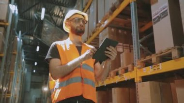 Fabrika deposunda tabletli bir adam. Depoda çalışan bir işçi bir tur atar..