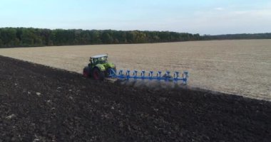 Sahada çalışan bir traktörün insansız hava aracı vurulması. Traktör sahada çalışıyor. İnsansız hava aracından çekilen bir traktörle tarlayı sürmek.