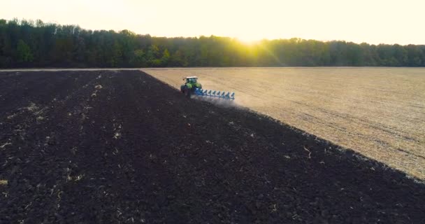 Le tracteur laboure le champ par le haut. Le tracteur travaille sur le terrain dans la soirée. Vue depuis le drone. tracteur moderne laboure le champ — Video