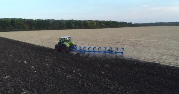 Egy terepen dolgozó traktor drónlövése. A traktor terepen dolgozik. Felszántani egy mezőt egy drónból kilőtt traktorral.. — Stock videók