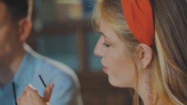 Kızla birlikte olan adam kokteyl içiyor. Bir kızla çıkan adam.