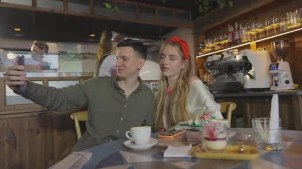 Mädchen und Jungen machen ein Selfie in einem Café. Mädchen macht Selfie mit einem Kerl — Stockvideo