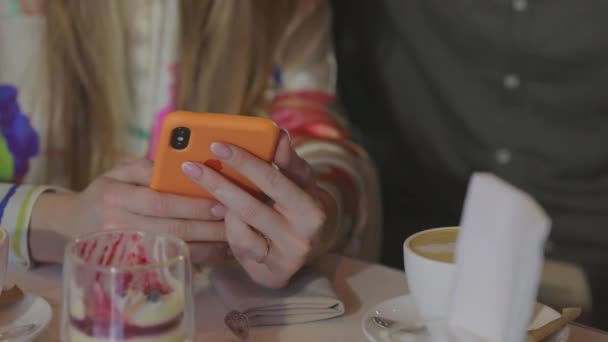 Dziewczyna trzyma telefon w dłoniach z bliska. Dziewczyna pokazuje coś na telefonie.. — Wideo stockowe