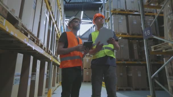 Engenheiros num armazém de fábrica. Dois trabalhadores em um armazém estão discutindo trabalho. — Vídeo de Stock