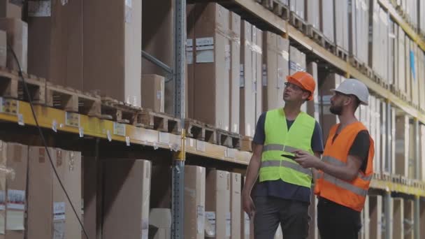 Des ingénieurs dans un entrepôt d'usine. Deux travailleurs dans un entrepôt discutent du travail. — Video