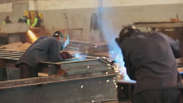 Dělník v továrně svařuje kovovou konstrukci. Tovární svářečka — Stock video