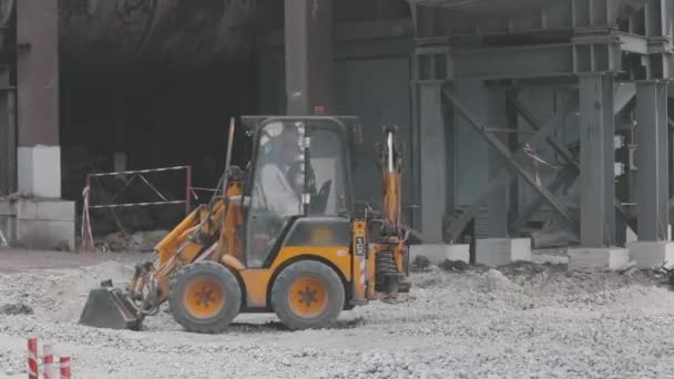 Bulldozer en el sitio de construcción, pequeña excavadora amarilla en el sitio de construcción. Bulldozer realiza trabajos en una obra de construcción — Vídeo de stock