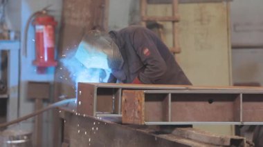 Kaynakçı metal bir parça topluyor. Kaynakçı fabrikada çalışıyor. Metal yapı kaynaklama