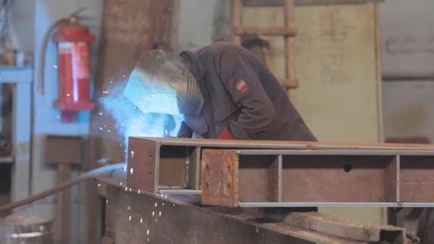 Svářeč sbírá kovovou část. Svářečka pracuje v továrně. Svařování kovové konstrukce — Stock video