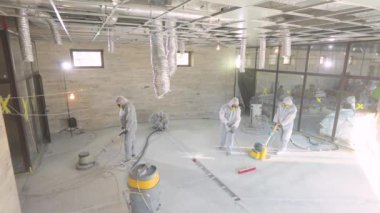 İnşaatçılar zemini özel ekipmanlarla cilalıyorlar. Beton yüzey öğütme. İnşaat alanında inşaatçılar