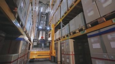 Forklift, depo zamanındaki kutuları, büyük sanayi deposunu, depodaki makinelerin hareketini yeniden düzenliyor.