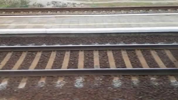Uitzicht vanaf de treinwagon naar de spoorweg. Zicht vanuit het treinraam op de treindwarsliggers — Stockvideo