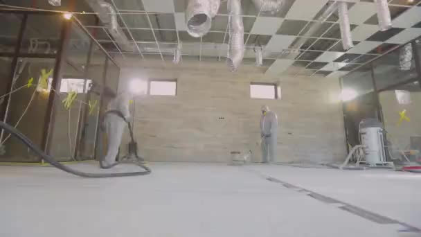 Construction professionals. Working process at a construction site. Workers in protective suits are grinding the concrete floor. Workers make concrete floor — Stock Video