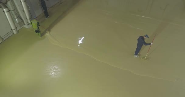 Självutjämnande golv på ett stort område, en arbetare häller självutjämnande golv i en fabriksverkstad. Häll självutjämnande golv. — Stockvideo