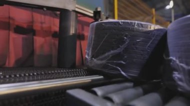 Modern bir konveyörde kabloyla makaraları paketlemek, otomatik makaraları kabloyla sarmak, fabrikada modern otomatik taşıyıcı.