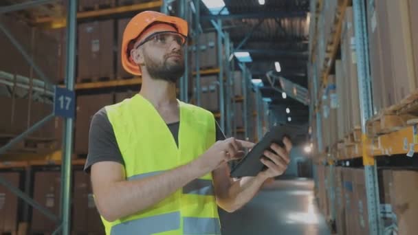 Directeur d'entrepôt d'une grande usine. Un manager avec une tablette dans un entrepôt vérifie les marchandises — Video