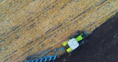 Traktör saha manzarasında çalışıyor. Tarlada traktörün üzerinden uçuyor. Traktör tarlayı sürüyor..