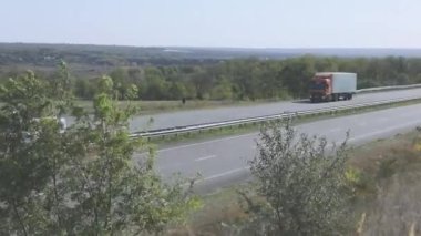Kamyon otoyolda gidiyor. Kamyon tarlaların ve ağaçların etrafındaki otoyolda gidiyor.