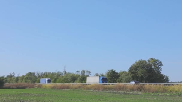 En vit vagn kör längs motorvägen i soligt väder. Lastbil på motorvägen — Stockvideo