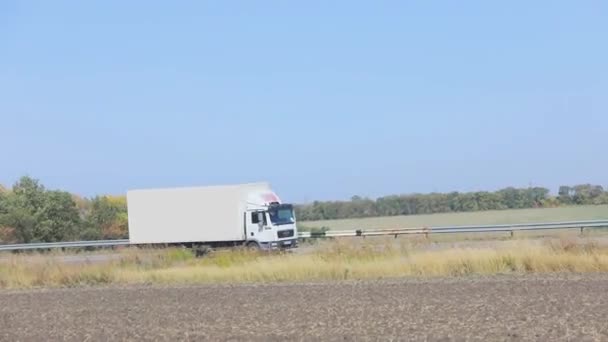 Un vagón blanco conduce a lo largo de la carretera en un clima soleado. Camión en la carretera — Vídeo de stock