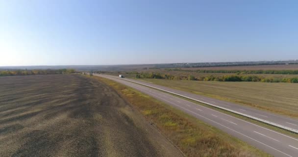 Un camion roule le long d'une belle route entre les champs vue de dessus. Un camion cargo roule le long de l'autoroute. Vue depuis un drone. — Video