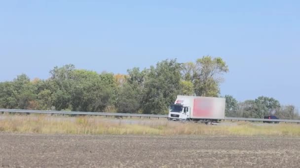 Вантажівка їде по трасі навколо полів і дерев. Вантажівка їде по шосе . — стокове відео
