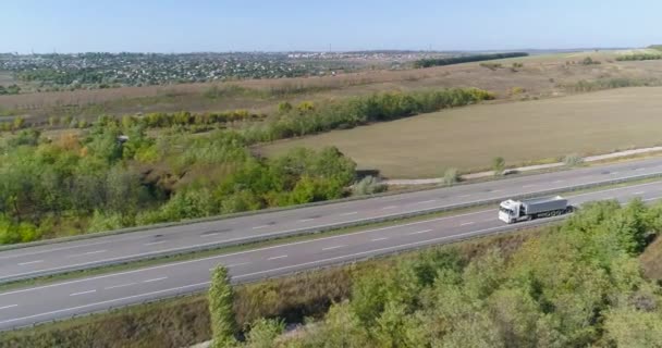 Een vrachtwagen rijdt langs een prachtige weg tussen velden bovenaanzicht. Er rijdt een vrachtwagen langs de snelweg. Uitzicht vanaf een drone. — Stockvideo