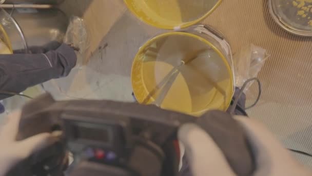 Um close-up de tinta amarela sendo mexido em um balde. Tinta agitando em um balde — Vídeo de Stock