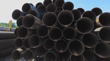 Geniş çaplı metal borulardan bak. Metal bir depoda büyük çaplı metal borular, açık hava deposunda büyük borular, sıra sıra yığılmış büyük çaplı borular.