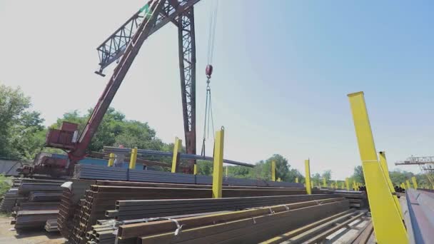 Carga de metal con la ayuda de una grúa pórtico, trabajo en un almacén, un almacén de metal al aire libre, transporte de productos metálicos — Vídeo de stock