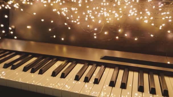 Synthesizer with New Years lights. Beautiful synth with Christmas decorations. Close-up synthesizer keys — Stock Video