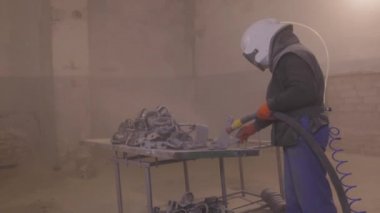 Parçayı zımparalıyorum. Fabrikada metal parçaları kumlamak. Kum püskürtme