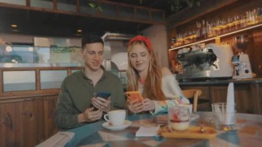 Kız ve erkek kahve dükkanında selfie çekiyorlar. Kız bir erkekle selfie çekiyor.