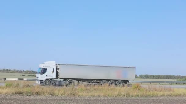 Bij zonnig weer rijdt er een witte wagen langs de snelweg. Vrachtwagen op de snelweg — Stockvideo