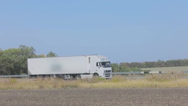 Biały wóz jedzie wzdłuż autostrady w słoneczną pogodę. Ciężarówka na autostradzie — Wideo stockowe