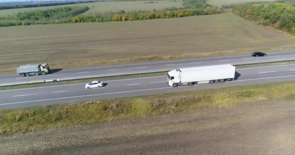 O caminhão dirige na estrada, campos no fundo. Transporte de mercadorias por caminhão. O caminhão dirige ao longo da estrada no meio dos campos agrícolas vista superior. — Vídeo de Stock