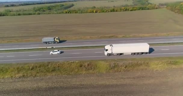 Biały wóz jedzie wzdłuż autostrady w dobrą pogodę. Ciężarówka jedzie wzdłuż tersy w słoneczną pogodę. Wóz jedzie piękną drogą. — Wideo stockowe