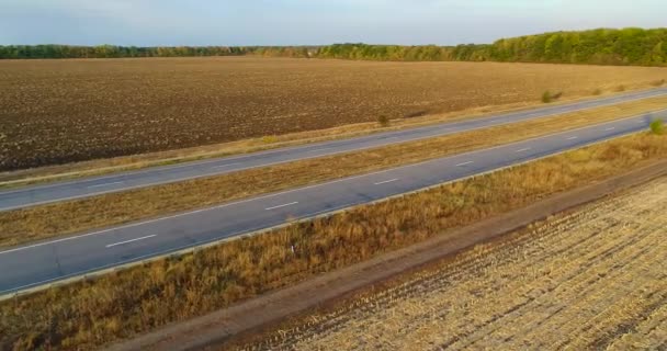 Un camion roule le long d'une belle route entre les champs vue de dessus. Un camion cargo roule le long de l'autoroute. Vue depuis un drone. — Video