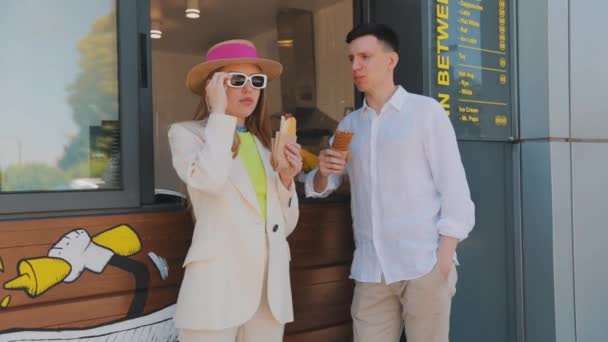 Un paio comprano hot dog. Fast food, street food. Una ragazza con un ragazzo compra un hot dog. — Video Stock