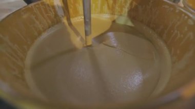 Kovada boya karıştırmak. Yakın plan sarı boya kovada karıştırılıyor.